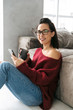 © Drobot Dean - Beautiful woman indoors in home on sofa using mobile phone.