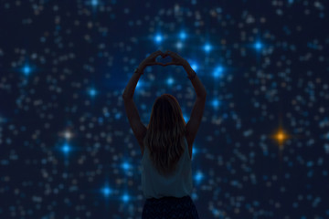 Wall Mural - silhouette of a girl holding heart-shape symbol for love on a starry night sky. my astronomy work.