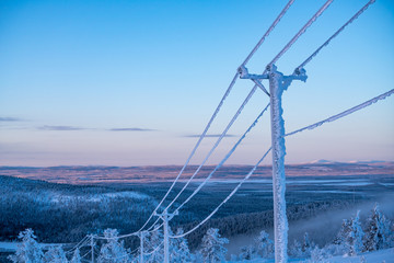 Frost and snow covered power lines during very cold winter against sky in Finland