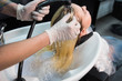 © strigana - Beauty concept - Professional hairdresser applying shampoo, washes color paint off and massaging hair of a customer. Woman having her hair washed in a hairdressing beauty salon
