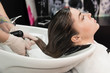 © strigana - Beauty concept - Professional hairdresser applying shampoo, washes color paint off and massaging hair of a customer. Woman having her hair washed in a hairdressing beauty salon