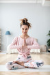 © BestForYou - Positive female in lotus pose on yoga mat on home interior.