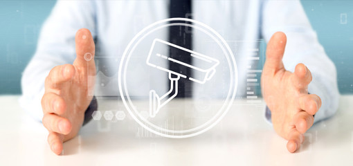 Poster - Businessman holding Security camera system icon and statistics data - 3d rendering