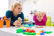 Toddler girl in child occupational therapy session doing sensory playful exercises with her therapist.