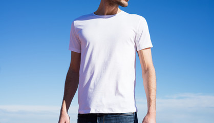 Photo of a man wearing white t-shirt. Blue sky on background