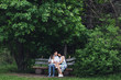 © Marina Varnava - friendly happy family resting on a wooden bench under the maple