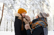 © Seventyfour - Side view portrait of happy mother tying scarf on cute little girl while having fun in winter forest, copy space