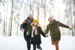 Portrait of playful family running in winter forest all smiling happily in sunlight, copy space