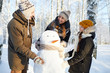 © Seventyfour - Portrait of happy family building snowman in winter forest and laughing, copy space