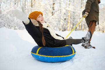 Wall Mural - Full length portrait of happy girl enjoying sleigh ride in beautiful winter forest, copy space