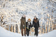 Full length portrait of happy family enjoying walk with dog in beautiful winter forest, copy space