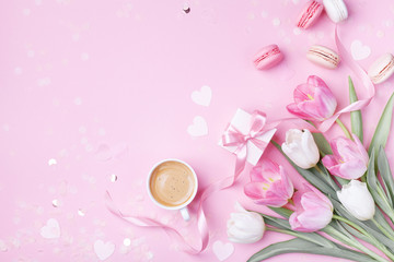 Wall Mural - Morning cup of coffee, cake macaron, gift box and spring tulip flowers on pink background. Beautiful breakfast for Women day, Mother day. Flat lay.