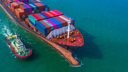 Container ship arriving in port, Tug boat and container ship going to deep sea port, logistic business import export shipping and transportation, Aerial view.