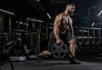 muscular man working out in gym doing exercises with dumbbells, strong male naked torso abs