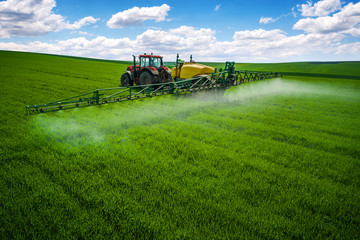 Wall Mural - Aerial view of farming tractor plowing and spraying on field