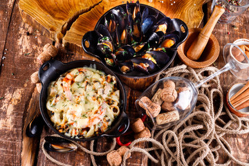 Tasty seafood in white sauce on a metal black plate.