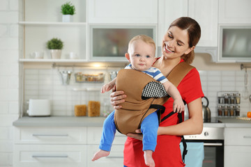 Sticker - Woman with her son in baby carrier at home. Space for text