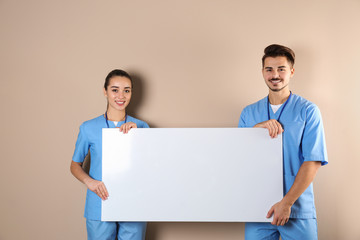 Canvas Print - Medical students with blank poster on color background. Space for text