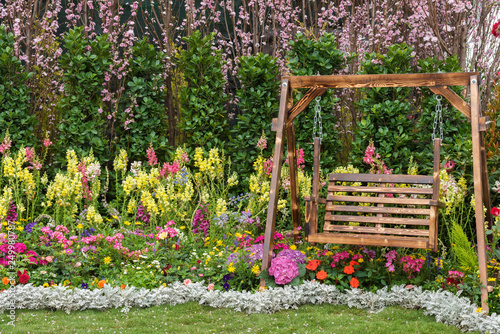 Fotografía Wooden swing seat in flower garden