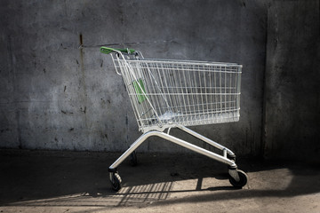 Empty shopping cart standing by concrete wall