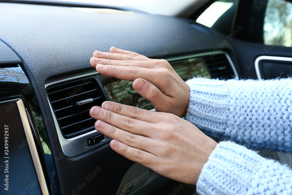 Woman checking operation of air conditioner in car