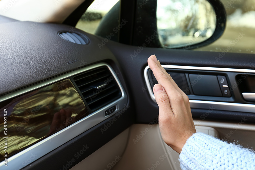 Woman checking operation of air conditioner in car