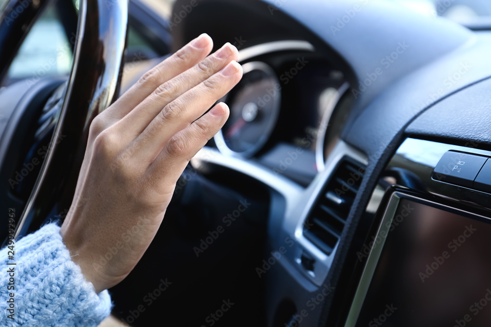 Woman checking operation of air conditioner in car