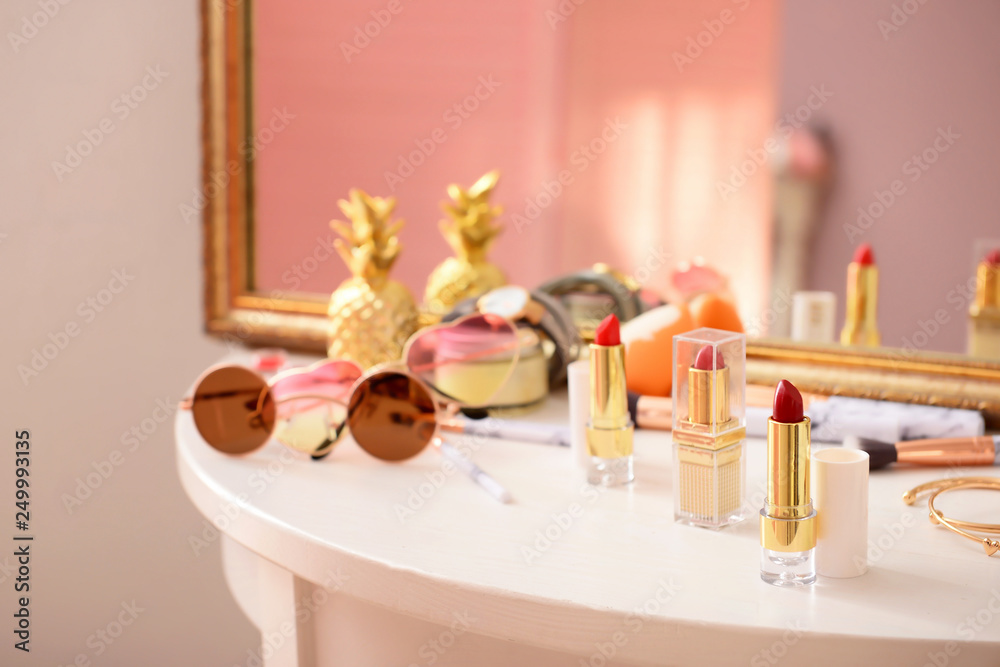 Makeup cosmetics with female accessories on dressing table with mirror