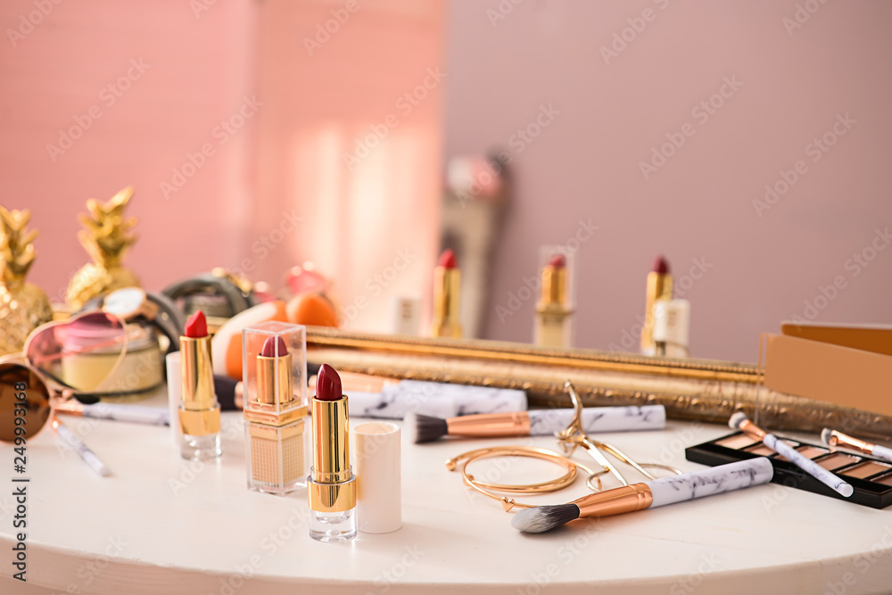 Makeup cosmetics with female accessories on dressing table with mirror