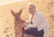 Portrait o happy attractive senior woman with her german shepard dog on the beach at autumn sunset