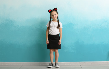 Portrait of stylish little girl near color wall