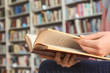 © Pixel-Shot - Young woman reading book in library, closeup