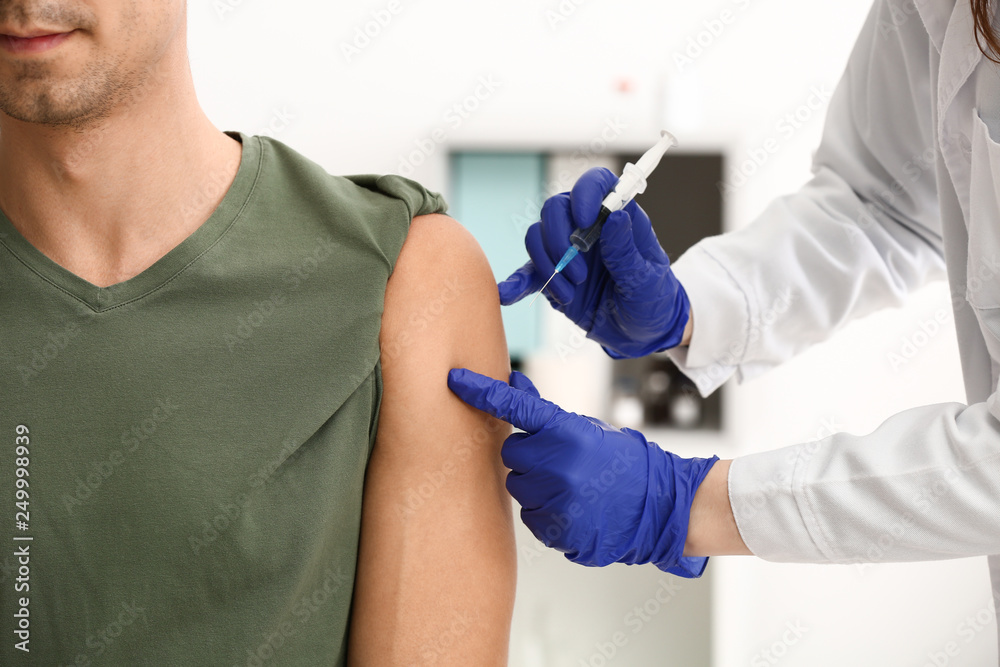 Doctor vaccinating male patient in clinic