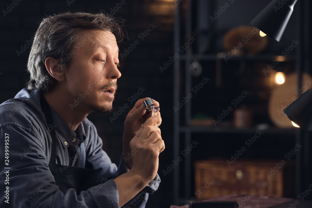 Jeweller examining gemstone in workshop