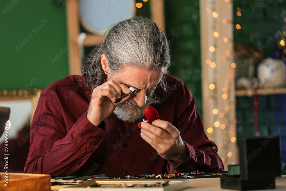 Jeweller examining adornment in workshop
