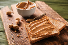 Toasted Bread With Tasty Peanut Butter On Wooden Board