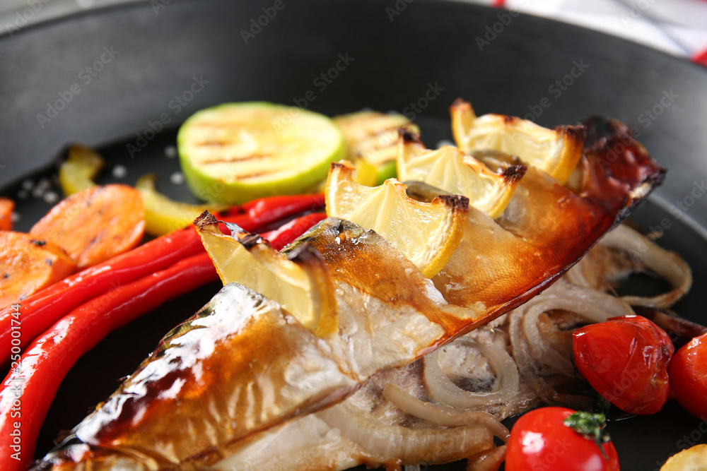 Frying pan with tasty mackerel fish and vegetables, closeup