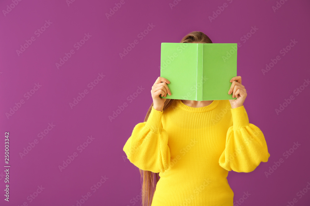 Beautiful young woman with book on color background