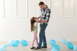 © Pixel-Shot - Cute little girl dancing on her father's feet in room with balloons