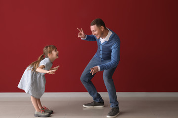 Canvas Print - Father and his cute little daughter dancing near color wall