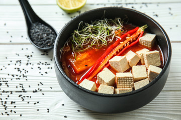 Tasty soup with tofu cheese in bowl on white table