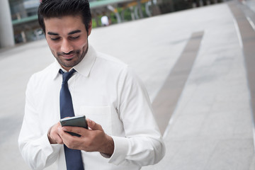 happy asian business man using smart phone; portrait of happy smiling successful Asian, north indian businessman using smart phone for app, internet connection, good connection concept