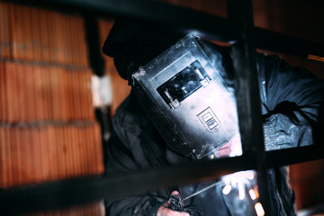 Wall Mural - Caucasian male worker using welding machine and tools for manufacturing steel railings