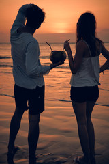 Couple drinking cocnut juice while watching the sunset over the ocean in Bali, Indonesia.