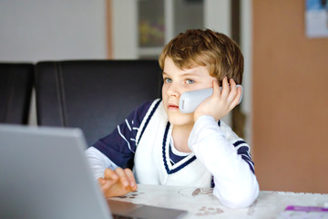 Wall Mural - Little kid boy making school homework on computer notebook. Happy healthy child searching information on internet. New media education, kid watching learning lessons on pc. Virtual classroom.