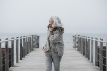 mature woman with long grey hair on a pier