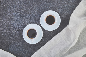 Two white cups of espresso on grey grunge background.