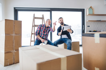 Wall Mural - A senior man helping his son with furnishing new house, a new home concept.