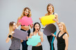 © Iryna - Group of five slim fitness women in sportswear holding varicoloured paper clouds indoor over grey wall background. Cope space text, diet, think, emotions, lose weight, choice and fitness concept.