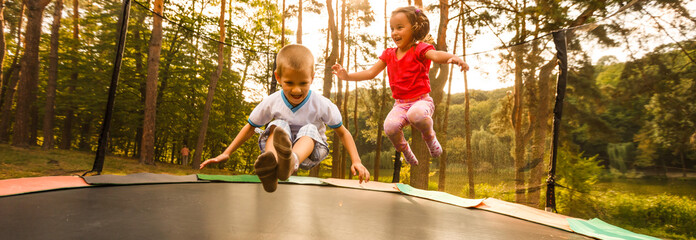 Little child enjoys jumping on trampoline - outside in backyard